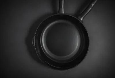 A plain steel frying pan photographed from directly overhead.