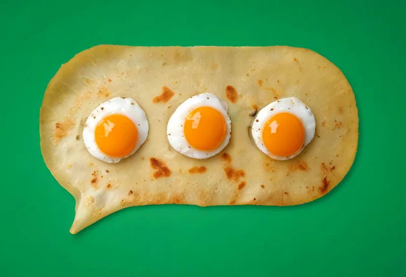 A golden crepe cut into the shape of a chat speech bubble, with three fried quail eggs in a row as the "typing" dots, on a green background.
