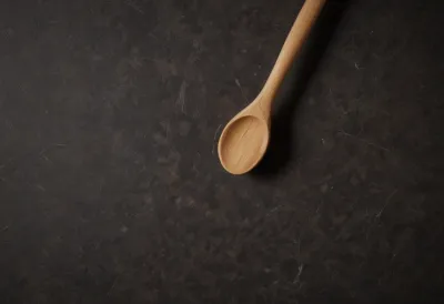 A plain wooden spoon lying on a kitchen counter, seen from above.