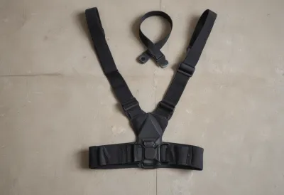 A black elastic heart-rate chest strap with its sensor pod lying flat on a plain concrete floor.