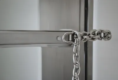A metal chain looped through the handle of a refrigerator door, photographed close up in flat daylight