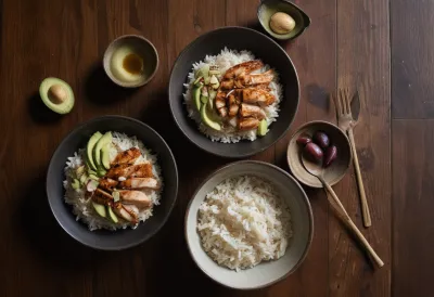 Three ceramic bowls on dark wood holding grilled chicken, steamed rice, and halved avocado with olive oil, shot from above