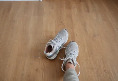 A pair of running shoes sitting on a wooden bedroom floor.