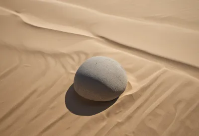 A smooth grey stone resting on fine sand.