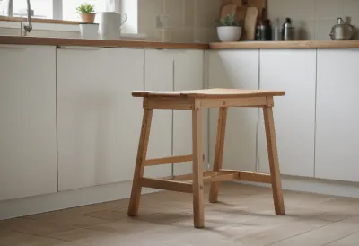 A plain wooden kitchen stool in an empty kitchen corner.