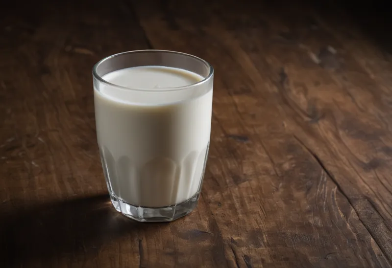 A plain glass of milk on a wooden table.